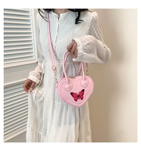 Detailed shot of a pink heart-shaped handbag with red butterfly pattern and thin strap
