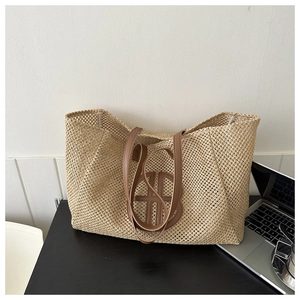 Detail of hand-woven straw tote bag with brown leather handles and circular hollow pattern
