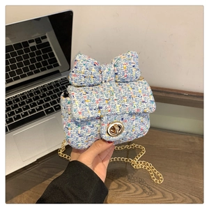 Detail of blue tweed crossbody bag with large bow and gold circular metal twist lock