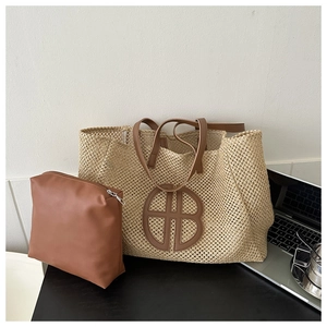 Close-up of beige woven straw tote bag with brown leather handles and inner pouch