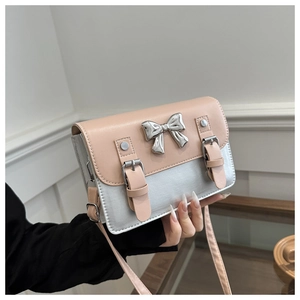 Detail of silver crossbody bag with pink flap and metallic bow accent in hand