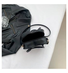 Detail view of heart-shaped black PU leather bag with gold hardware and dual zippers