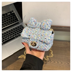Detail of blue tweed crossbody bag with bow decoration and gold chain strap