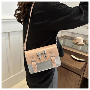 Detail of the chic bow knot metal clasp on a small contrast color PU leather flap bag