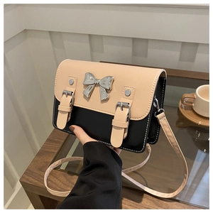 Detail of contrast bow crossbody bag with beige flap and silver ribbon buckle