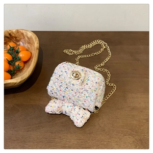 Detailed macro view of a pink tweed crossbody bag featuring a golden bow and twist lock clasp