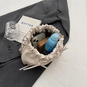 Sac seau crème plissé avec nœuds décoratifs et bandoulière chaîne sur veste grise