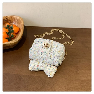 Detail of tweed mini crossbody bag featuring a large bow and gold cylindrical twist lock