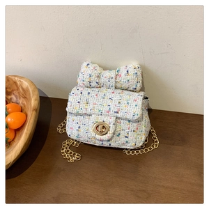 Detail of multi-color tweed mini bag featuring a large bow and gold metal swivel lock