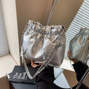 Silver pleated drawstring bucket bag with decorative bows and metallic chain strap