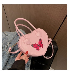 Detail of pink heart-shaped handbag with butterfly print and golden hardware accents