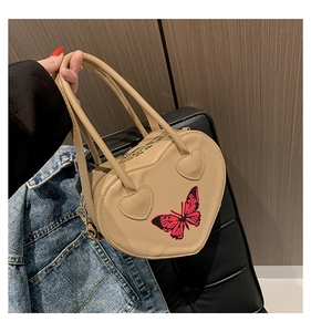 Beige heart-shaped handbag featuring a red butterfly print and metal zipper closure