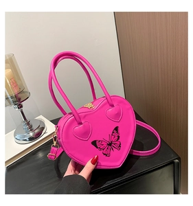 Detail of heart-shaped handbag in bright rose red featuring a black butterfly print pattern