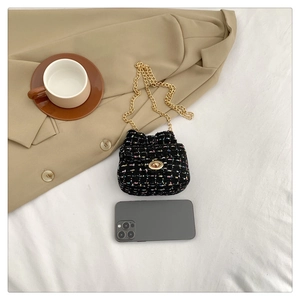 Mini black tweed crossbody bag with gold chain strap shown next to a smartphone
