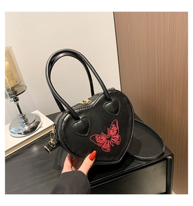 Detail of heart-shaped black leather bag featuring a vibrant red butterfly print