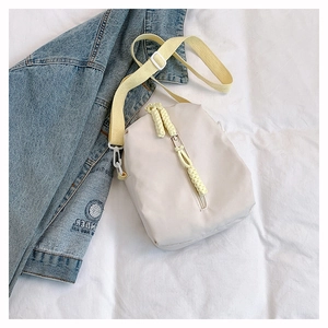 Detail of nylon crossbody bag with vertical zipper and yellow woven zip pullers