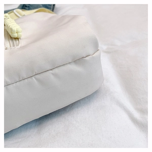 Detail of cream nylon fabric texture with yellow strap and woven zipper puller