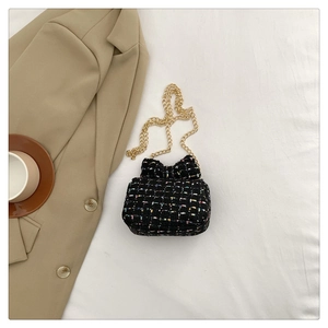 Detail view of mini black tweed crossbody bag with bow clasp and gold chain strap