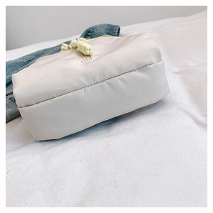 Detailed close-up of a beige nylon crossbody bag with a distinctive yellow rope knot detail