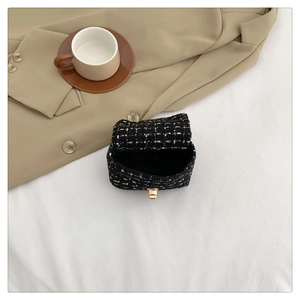 Macro detail of mini tweed flap bag with gold twist lock and elegant woven texture