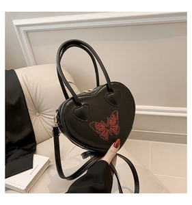 Detail of heart-shaped black leather handbag with red butterfly print and dual handles