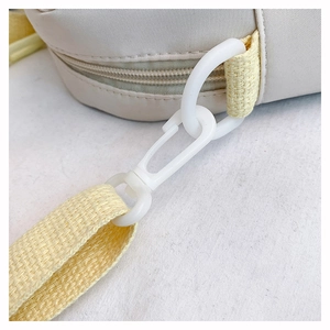 Detail of the white plastic swivel hook and yellow nylon strap on the beige shoulder bag