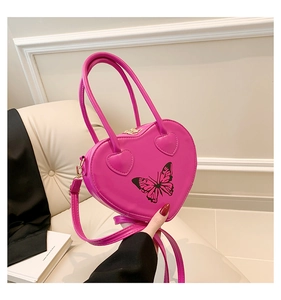 Close-up of pink heart-shaped leather handbag with a black butterfly print detail