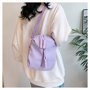 Detail of light purple crossbody bag showing braided zipper pulls and durable nylon texture