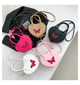 Flat lay of heart-shaped handbags in five colors with red butterfly patterns
