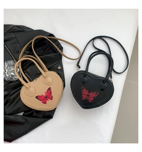Detail of heart-shaped bags with red butterfly print in black and beige colors