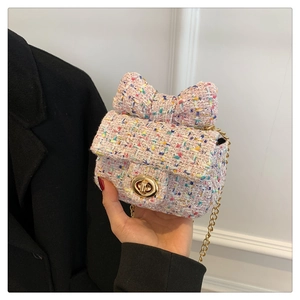 Close-up of pink tweed crossbody bag with bow detail and golden chain strap