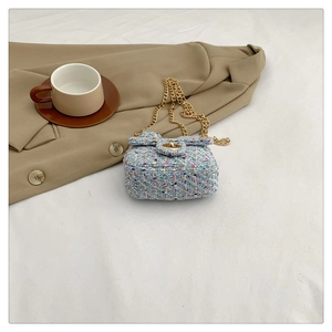 Detailed macro view of a blue tweed mini crossbody bag with golden chain and bow detail