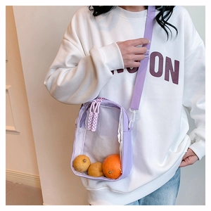 Detail view of light purple transparent PVC crossbody bag worn by a model in warm light