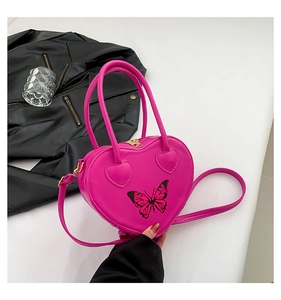 Detailed view of magenta heart-shaped leather bag with black butterfly print and dual handles