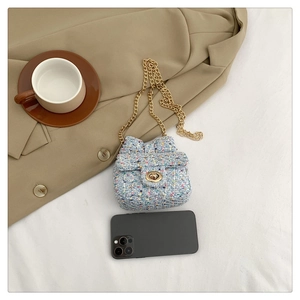 Macro detail of mini light blue woven crossbody bag with gold chain and round lock