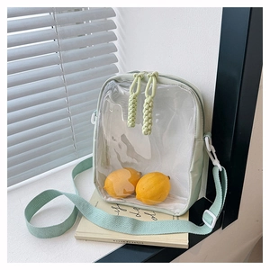 Detailed shot of mint green transparent PVC crossbody bag featuring woven zipper pulls