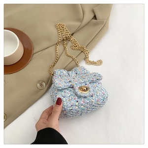 Close-up of light blue tweed crossbody bag with gold chain strap on a blazer