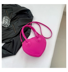 Detail view of heart-shaped handbag in rose pink faux leather with double handles