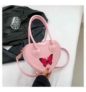 Close-up of heart-shaped pink leather bag with exquisite butterfly embroidery detail