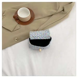 Detail of multi-color tweed mini flap bag showing golden twist lock and black interior lining