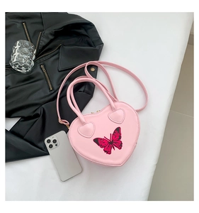 Detailed close-up of pink heart-shaped bag with butterfly embroidery and leather texture