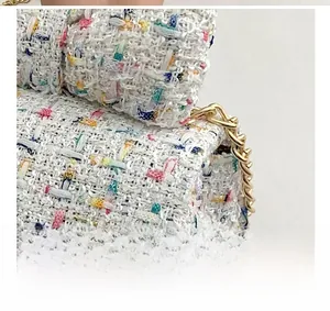 Close-up of multicolored tweed fabric texture and pale gold metal chain link detail