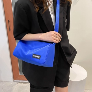 Electric blue nylon barrel crossbody bag with Fashion patch on black blazer model