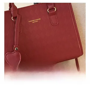 Gros plan d'un sac cabas rouge avec motif matelassé et charmant pendentif en cœur