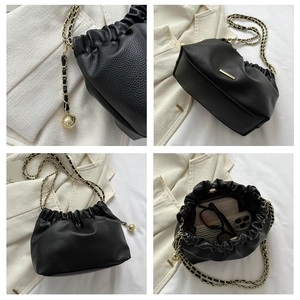 Détails du sac seau noir en cuir grainé avec bandoulière chaîne et pendentif doré