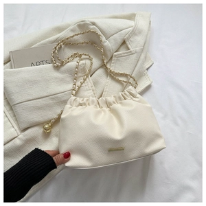 Gros plan du sac froncé blanc avec texture cuir grainé et détails de bandoulière dorée