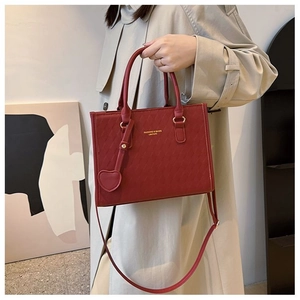 Λεπτομέρεια κόκκινης καπιτονέ τσάντας με χρυσά γράμματα και μενταγιόν καρδιά