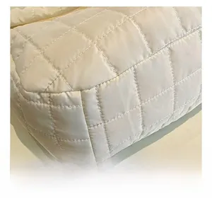 Detail showing high-quality quilted square stitching on beige puffer shoulder bag