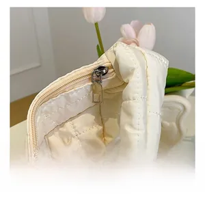 Detailed macro view of the smooth metal zipper and quilted cream fabric on the tote bag