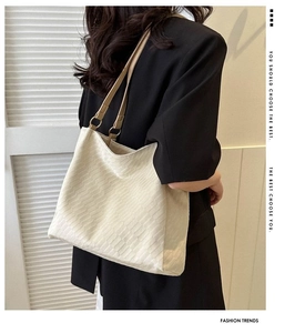Detail view of beige textured tote bag showing geometric patterns and leather straps